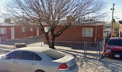 A silver car is parked in a lot with a tree and a red car in the background.