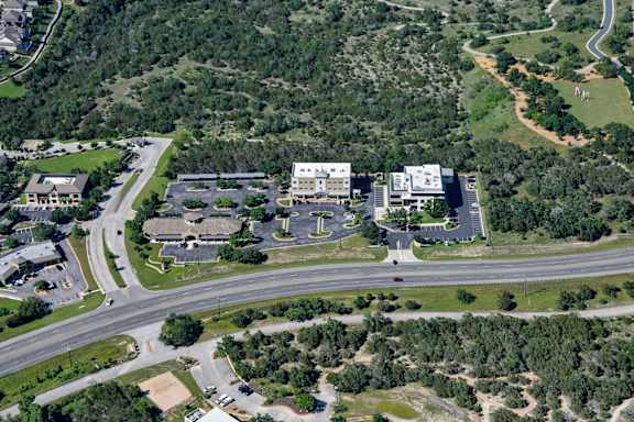 A bird's eye view of a roundabout with a building complex in the background.