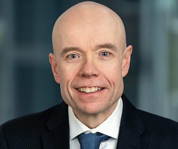 A bald man with a blue tie and a white shirt.
