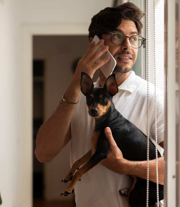 A man holding a dog looking out a window.