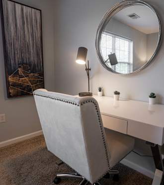 A white desk with a chair and a mirror in a room at Meadowbrook Apartments, Lowell, IN, 46356.