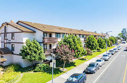 A row of houses with cars parked on the street.