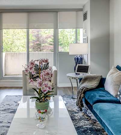 A modern living room with a blue couch and a dining table with chairs.