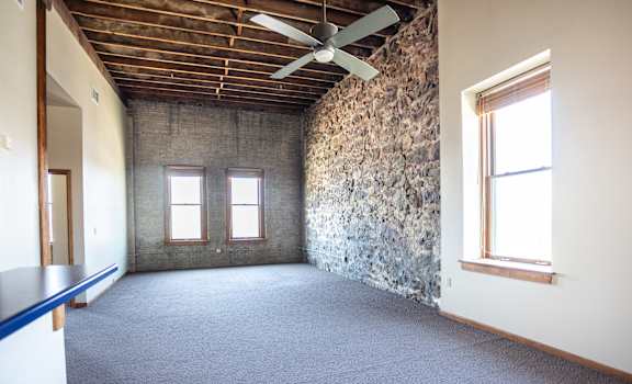 A room with a stone wall and a ceiling fan.