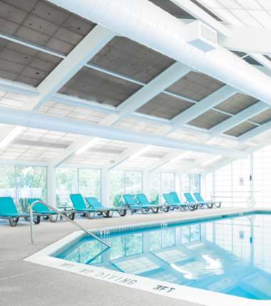 A large indoor swimming pool with lounge chairs on the side.