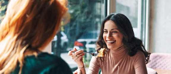 two women sitting at a table eating a hamburger