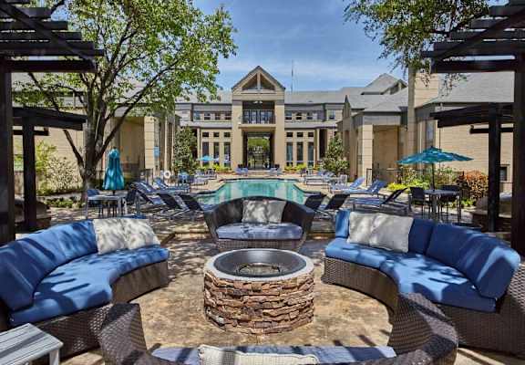 a patio with couches and a fire pit in front of a building