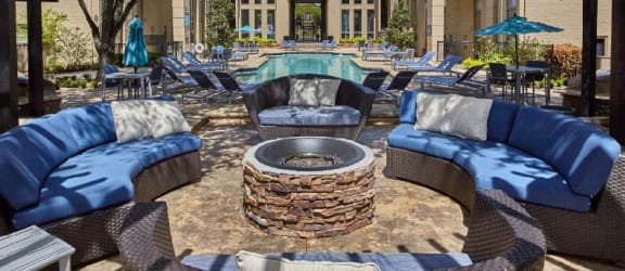a patio with couches and a fire pit in front of a building
