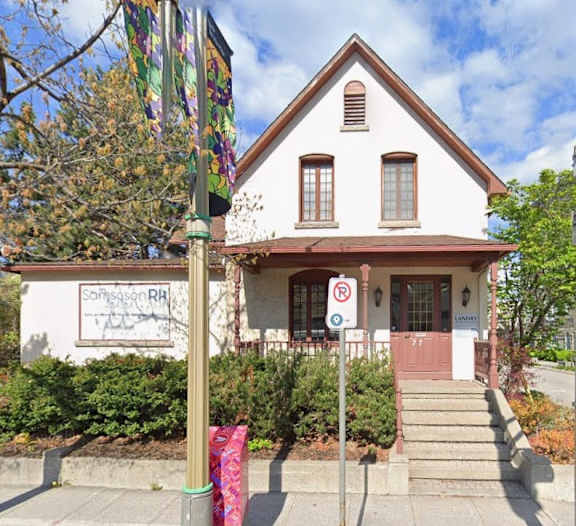 A white building with a red door and a no parking sign in front.