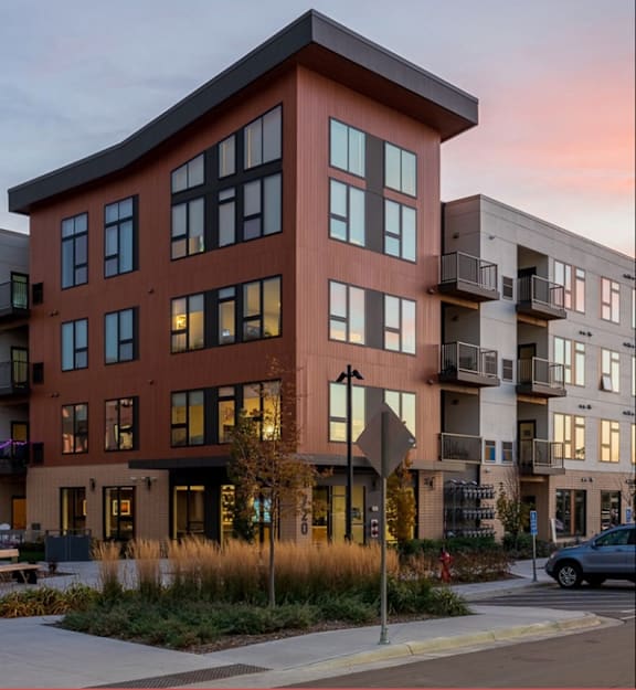 Exterior view of luxury apartment residences at sunset featuring modern architecture, balconies, and landscaped grounds.