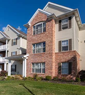 A large two-story apartment building with a red brick facade and white trim.