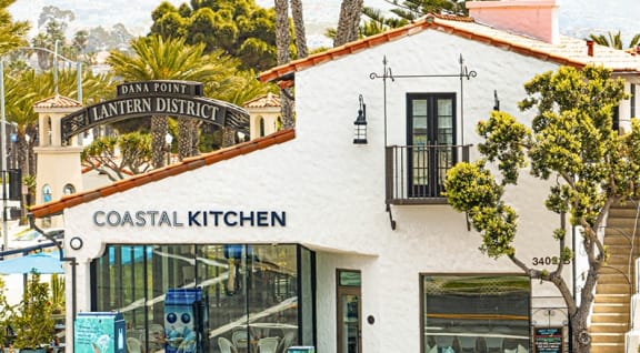 the facade of a coastal kitchen restaurant with a sign that reads coastal kitchen