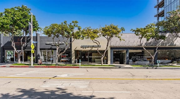 an empty street in front of a shopping center with trees
