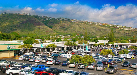 a parking lot full of cars with a mountain in the background