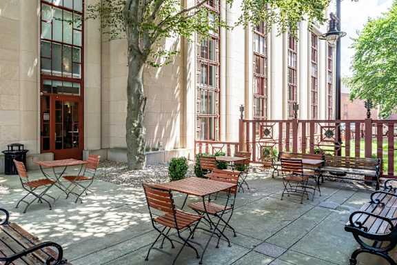 A patio with tables and chairs is surrounded by a building.