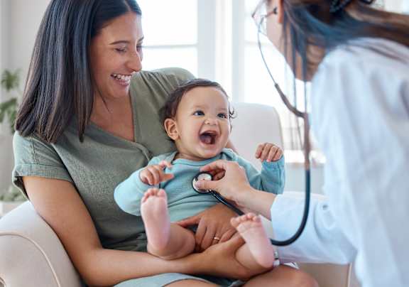 A doctor is checking the heartbeat of a baby with a stethoscope.