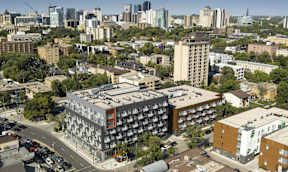 A cityscape with a large building in the foreground and smaller buildings in the background.