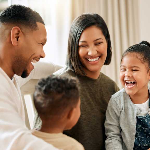 A family of four is sitting together and laughing.