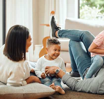A family of four is sitting on the floor in a living room.