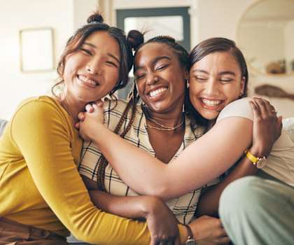 a group of women sitting on a couch hugging each other