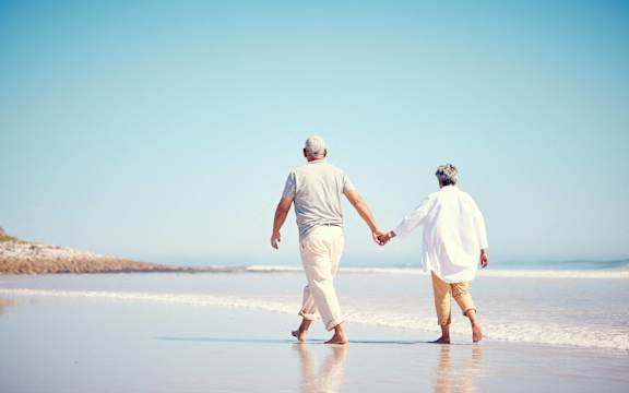 an older couple walking on the beach holding hands