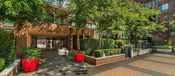 A courtyard with a building in the background and red planters in the foreground.
