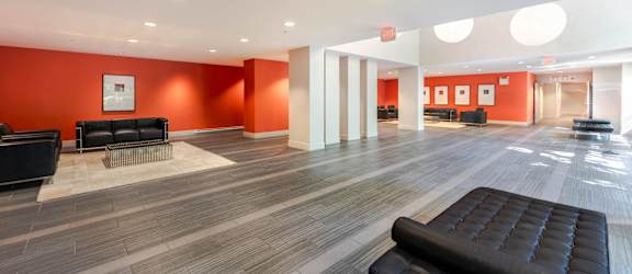 A spacious waiting room with black leather chairs and orange walls.