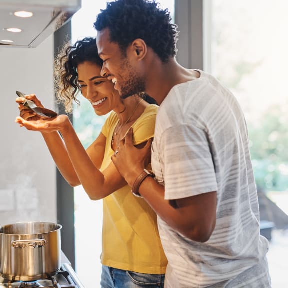 a man and woman standing in a kitchen looking at a smartphone at Northern Lights a Lifestyle-Driven Community, West Fargo, ND