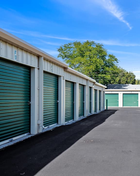 A long row of storage units with green doors.