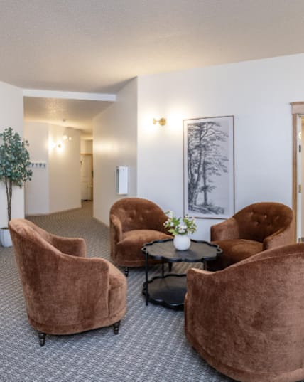 A room with brown chairs and a painting of a horse on the wall. at Eighth Street Manor  Apartments, Fargo, ND