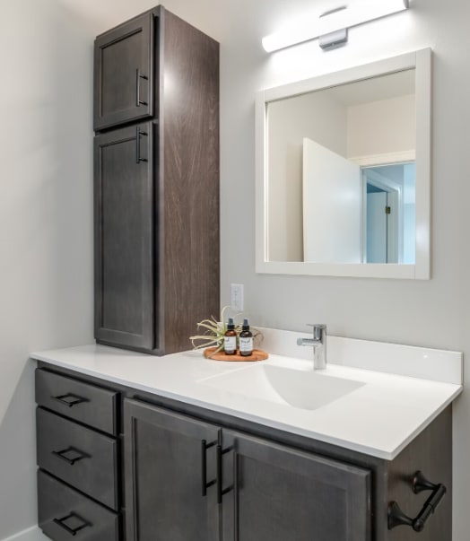 A bathroom with a sink, mirror, and cabinets.