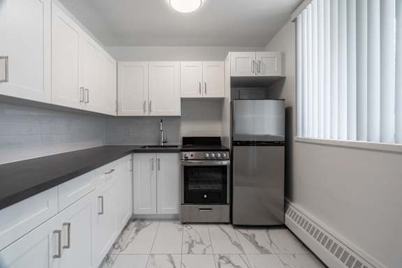 A kitchen with white cabinets and a black countertop. at 177 Saint George in Toronto, CA