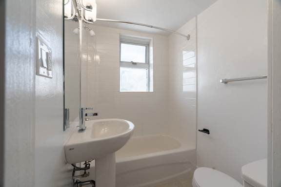 A white bathroom with a sink, toilet, and bathtub at 391 Sherbourne Apartments, Toronto