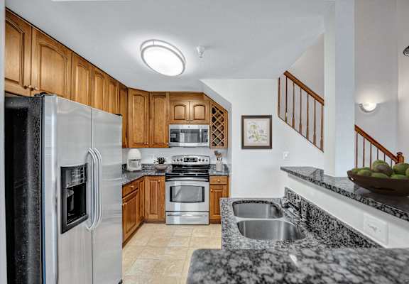 A kitchen with a refrigerator, sink, and stove.