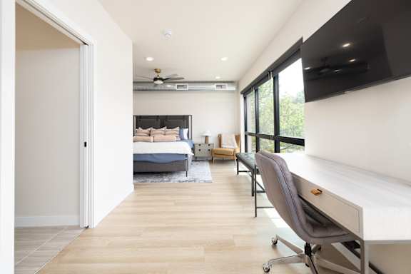 A bedroom with a bed, chair, and a television.
