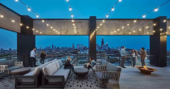 A rooftop patio with people and string lights. at The Mason Apartments, Illinois, 60607