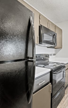 an apartment kitchen with black appliances and a black refrigerator