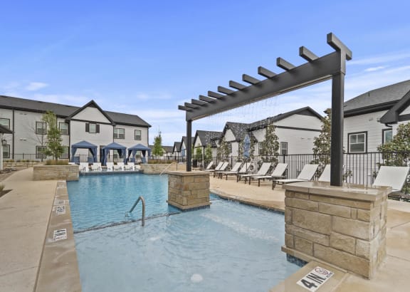 a swimming pool with lounge chairs and buildings in the background