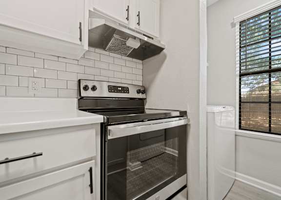 A modern kitchen with a stove and oven built into the cabinetry. at Polo Clubs Apartments, Austin, TX 78729