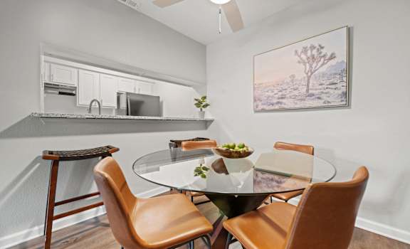 a dining area with a glass table and four chairs