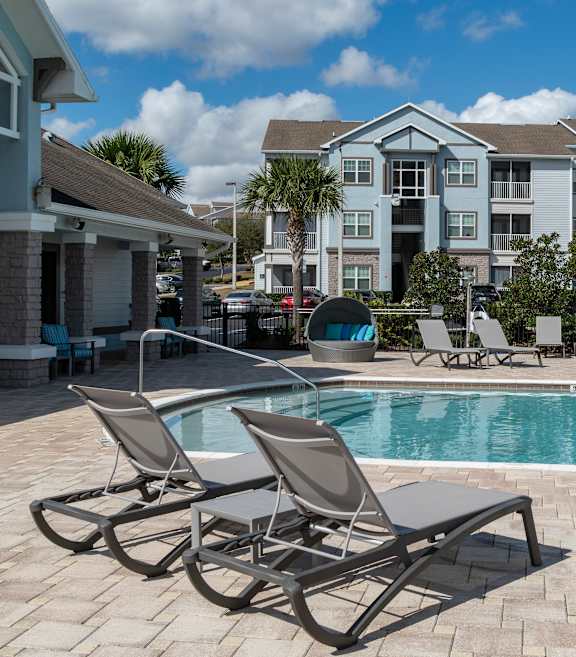 a swimming pool with chaise lounge chairs and a resort style building in the background