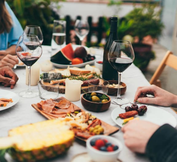 a group of people sitting around a table with wine and food