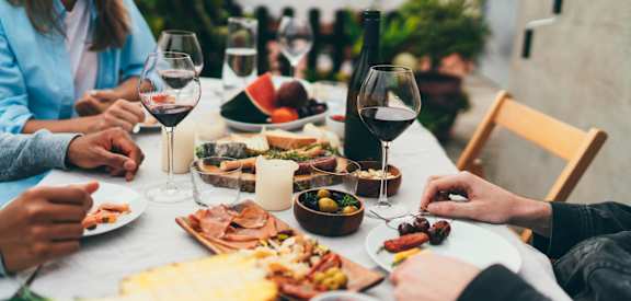 a group of people sitting around a table with wine and food