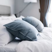 a bed with blue and white pillows and white sheets