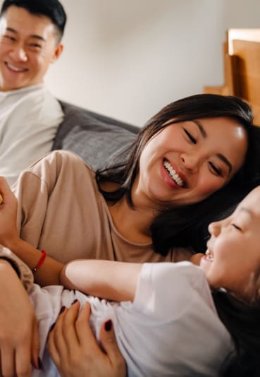 a mother and father lie on a bed with their daughter while the daughter eats a sandwich at Casa Blanca Apartment Homes, Washington