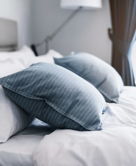 a bed with blue and white pillows and white sheets