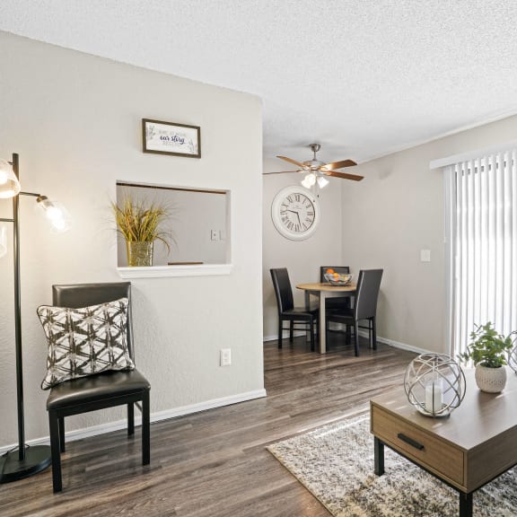 an open concept living room and dining area with a white dining table and rattan chairs