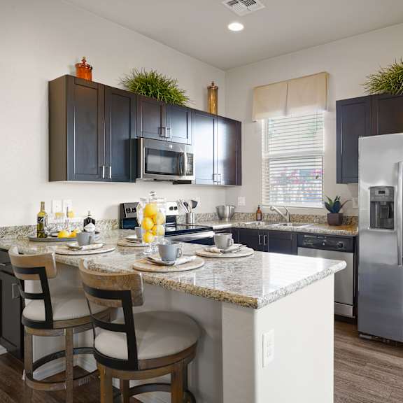 a kitchen with stainless steel appliances and a counter with bar stools at Bella Grace, Chandler, AZ