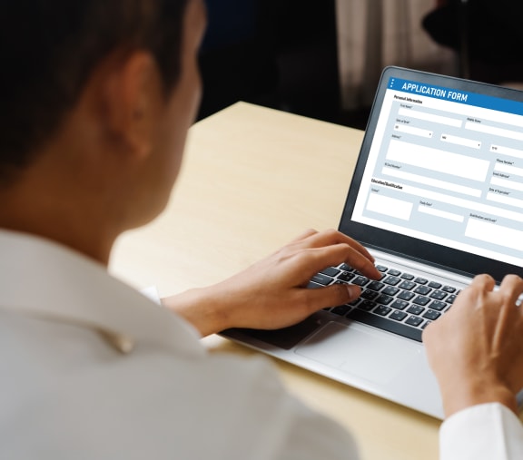 a woman typing on a laptop computer with an appointment scheduler on the screen