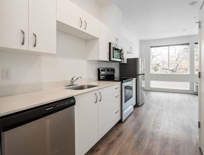 a kitchen with white cabinets and stainless steel appliances and a window